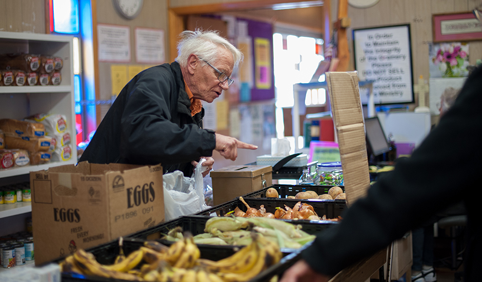 An old man choosing vegetables in a supermarket