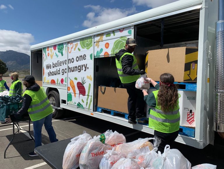 Volunteers unload prepared bags of food for a drive-through style distribution